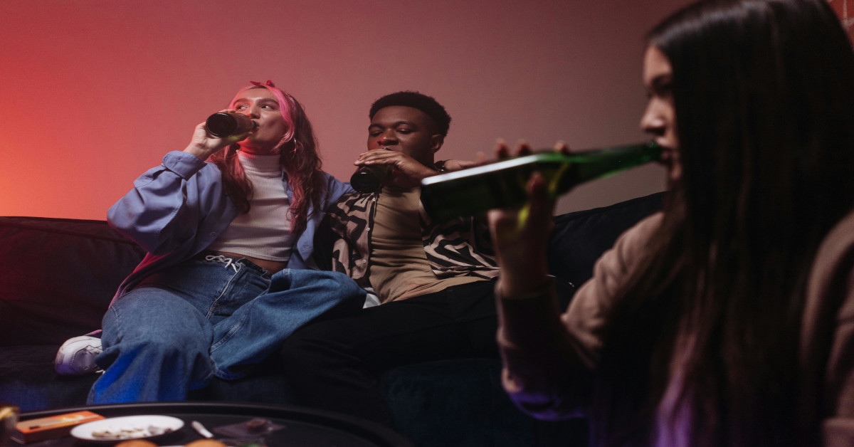 A group of friends drinking alcohol on the couch.