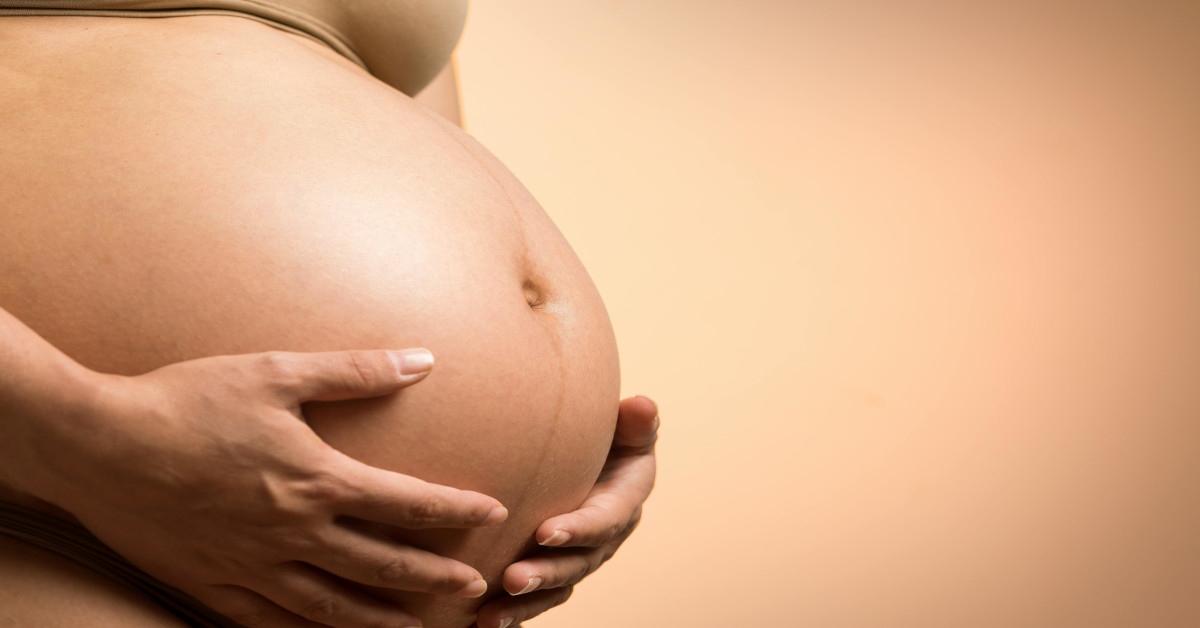 A pregnant woman holding her belly.