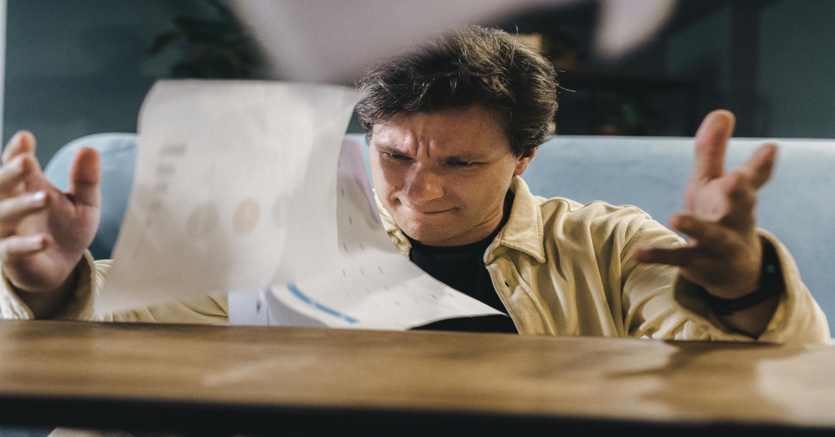 An agitated man throwing his papers.