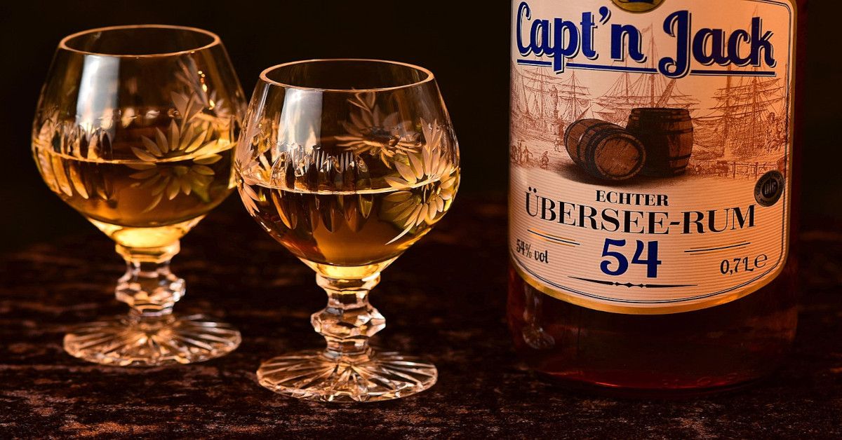 Two glasses of rum with a bottle of rum standing next to it.