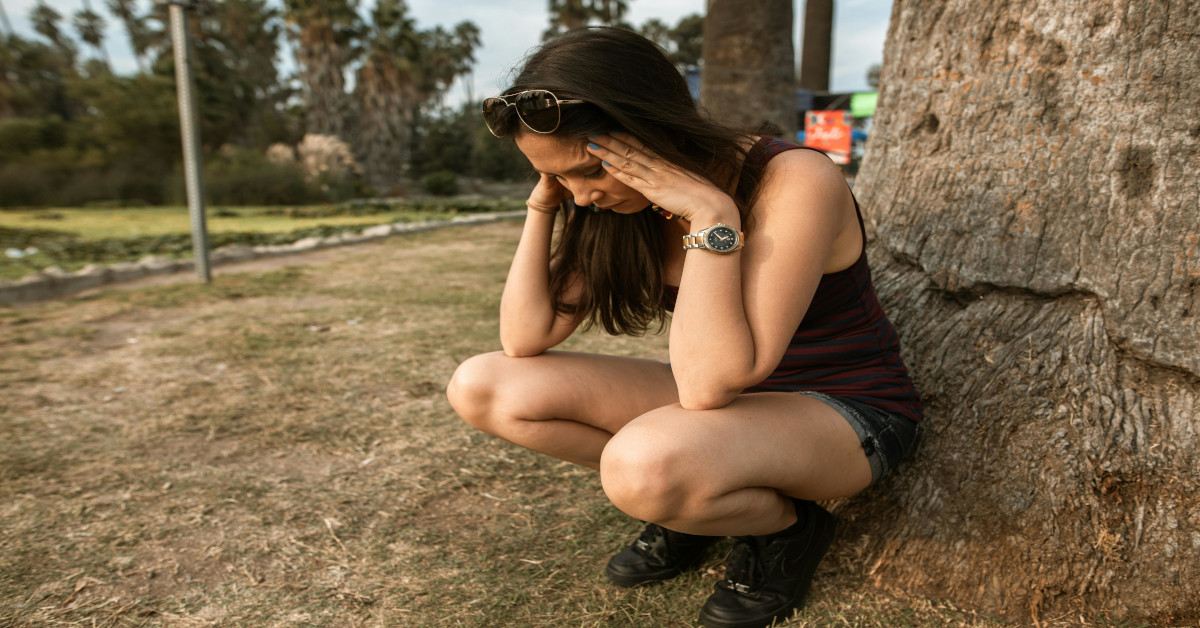 An anxious woman holding her head with her both hands while kneeling.