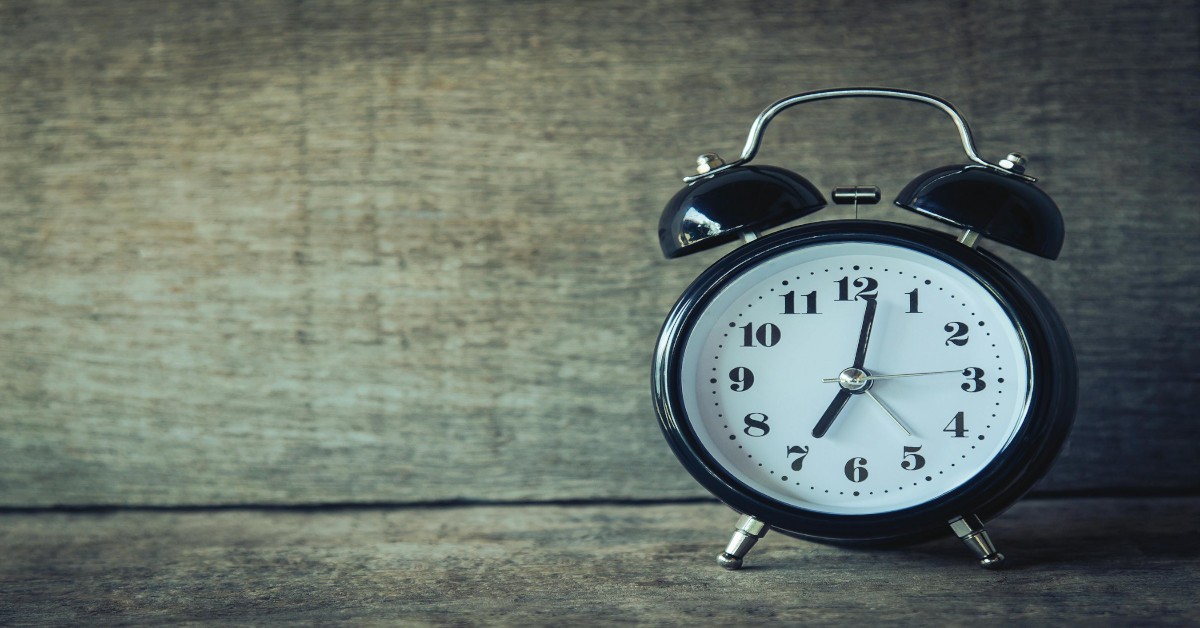 A black analog clock sitting on a table.