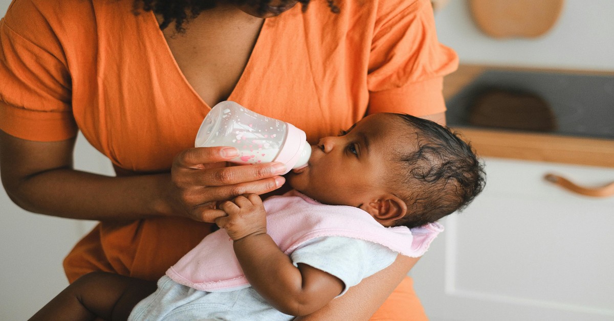 A black woman feeding her child milk.
