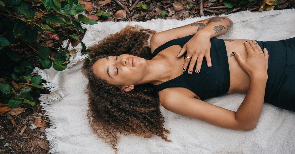 A black woman lying on her back on a white cloth.