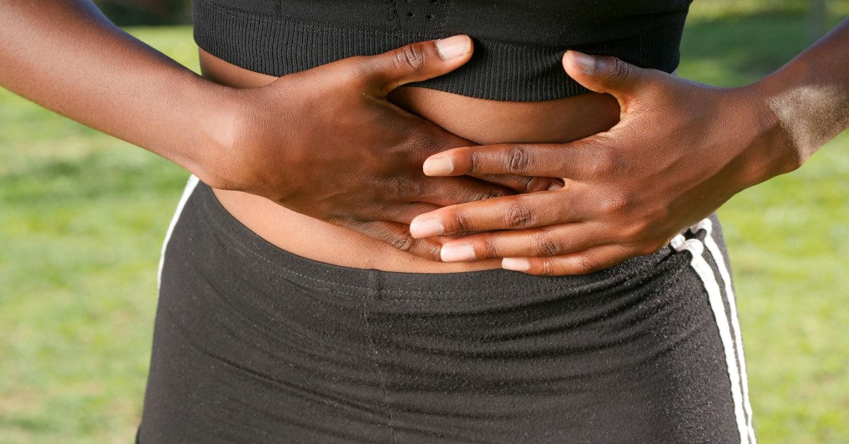 A black woman holding her stomach in pain.