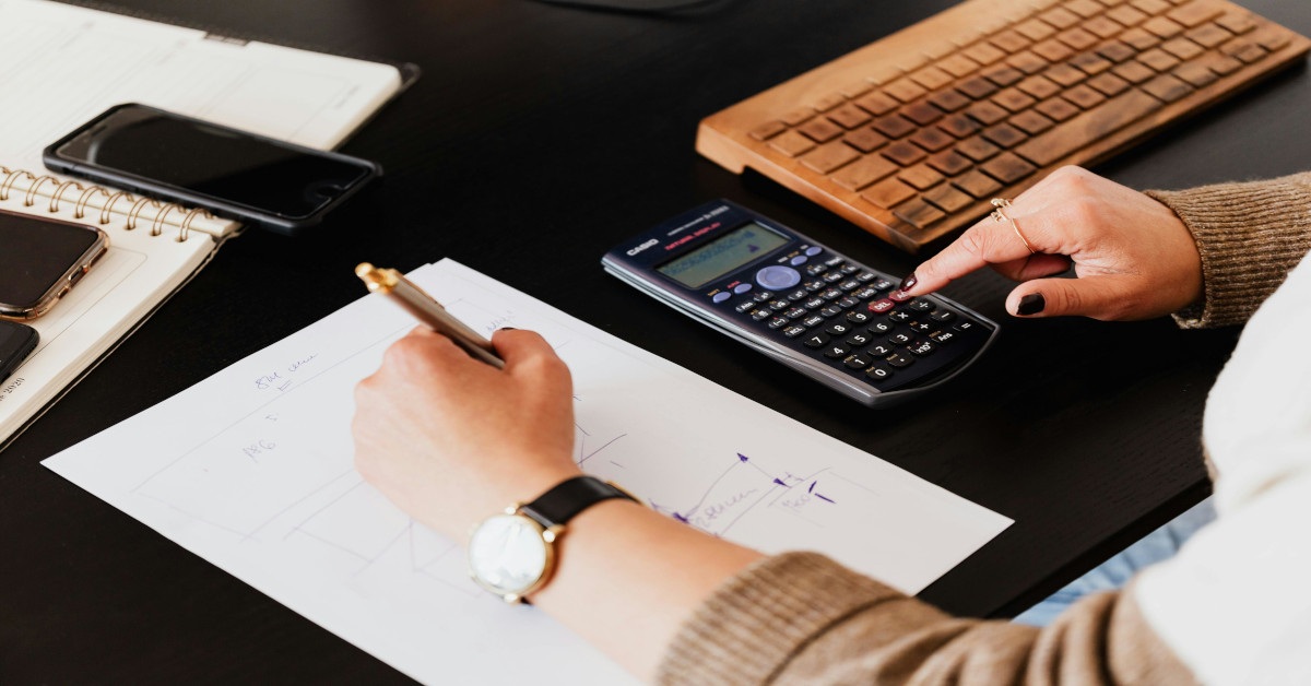 A bookkeeper taking notes while operating a calculator.