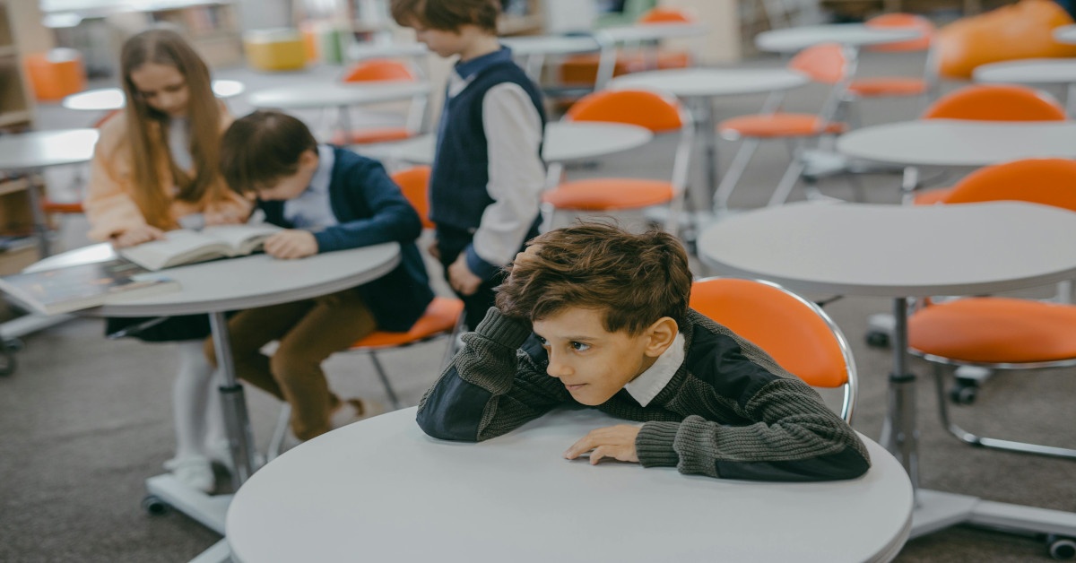A boy sitting alone, away from his fellow students.