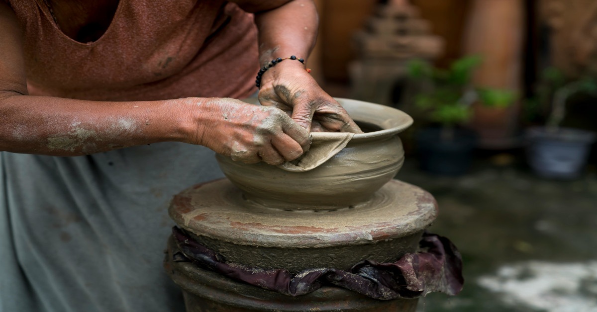A woman in the process of crafting a clay pot.