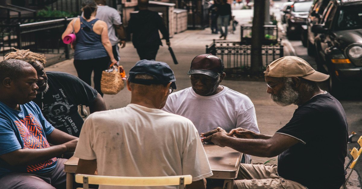 Dark skinned individuals engaging in the community while sitting in a group.