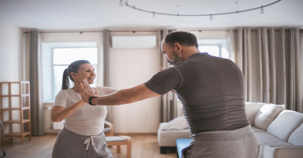 A mature couple doing yoga together while smiling.