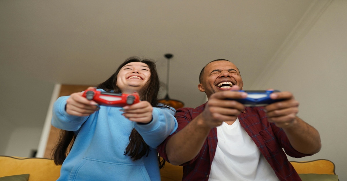 A couple gaming together while smiling.