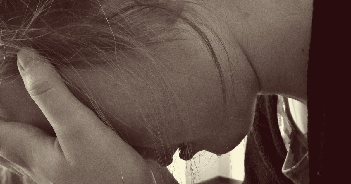 Image of a desperate woman crying while holding her head.