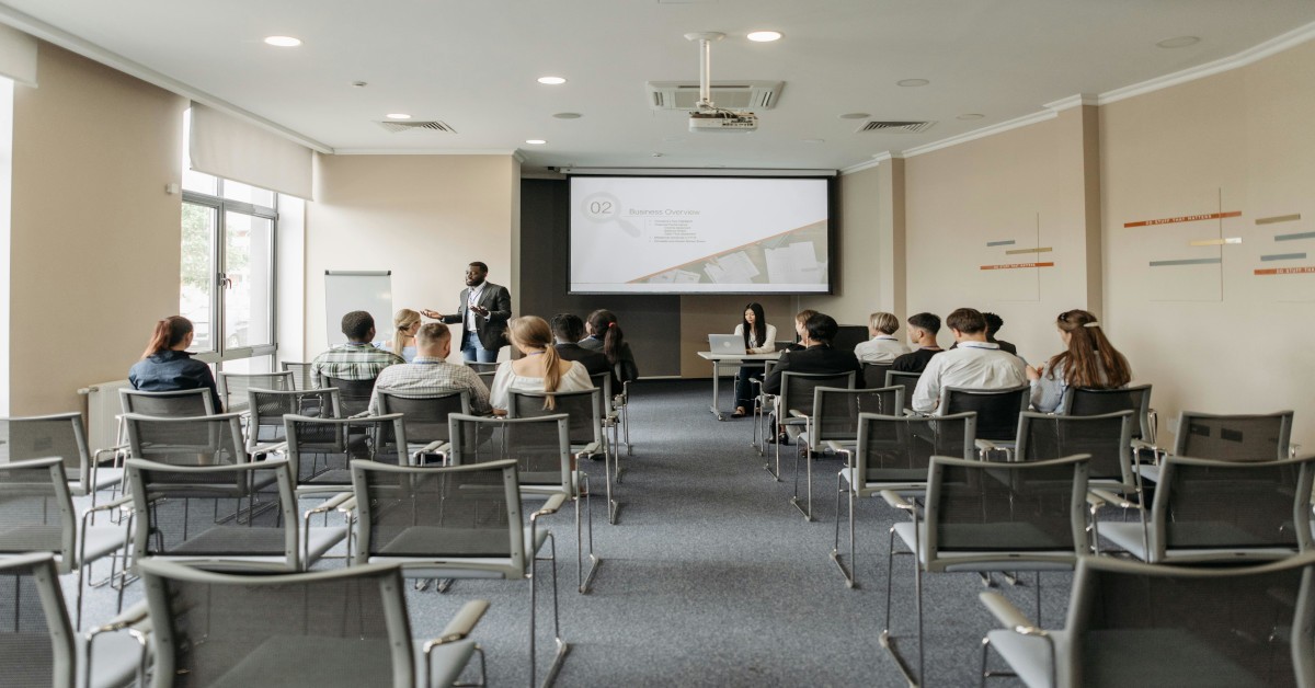 A man in a suit giving a business presentation to people sitting in chairs.