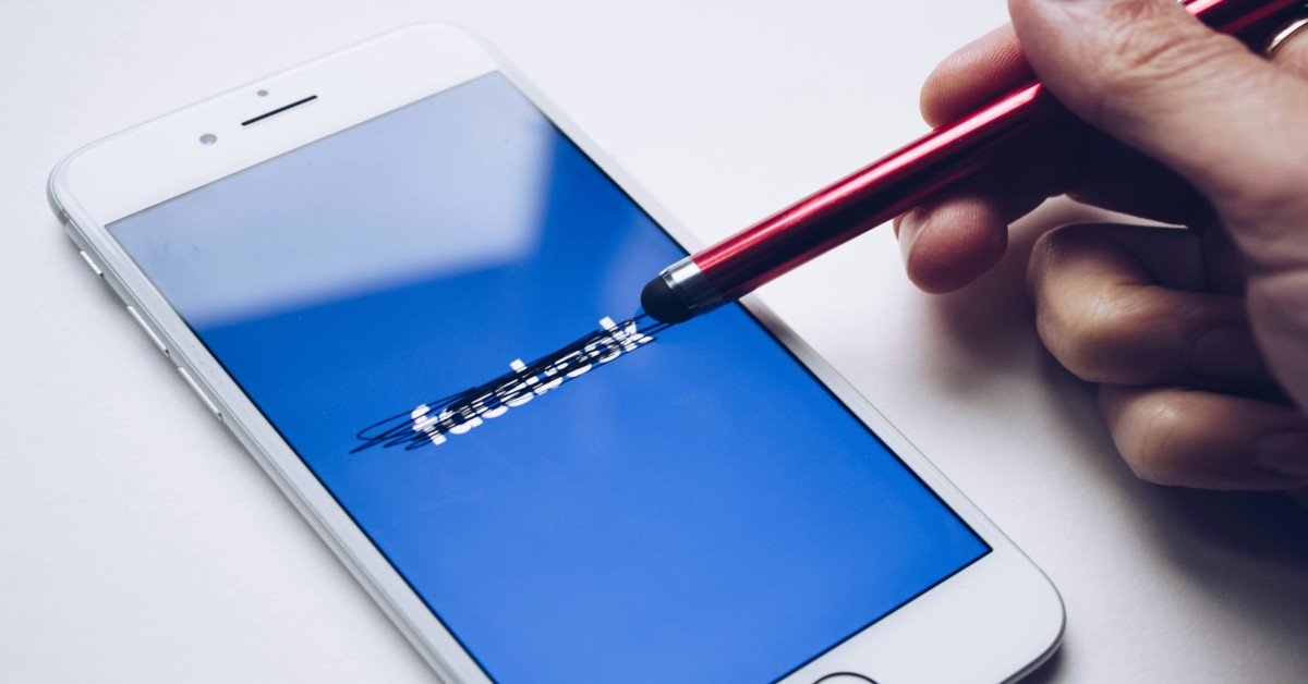 A pen crossing out the word "Facebook" on their cellphone.