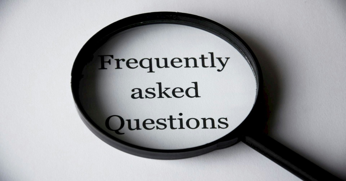 A magnifying glass is going over the sentence "Frequently asked Questions" that is written in black on a white background.