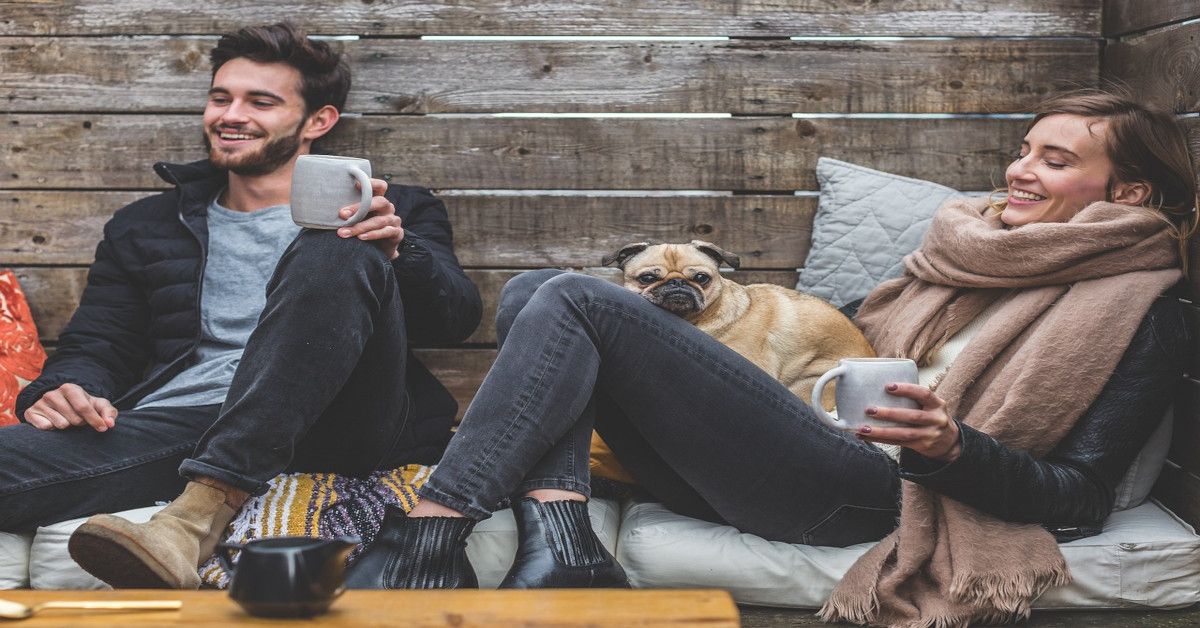A happy couple drinking a cup of coffee while smiling.