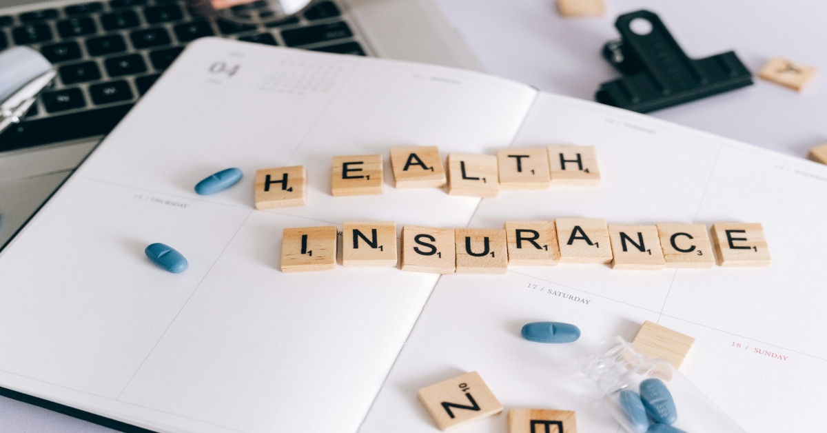 The sentence "health insurance" was made with Scrabble blocks on a table with pills around it.