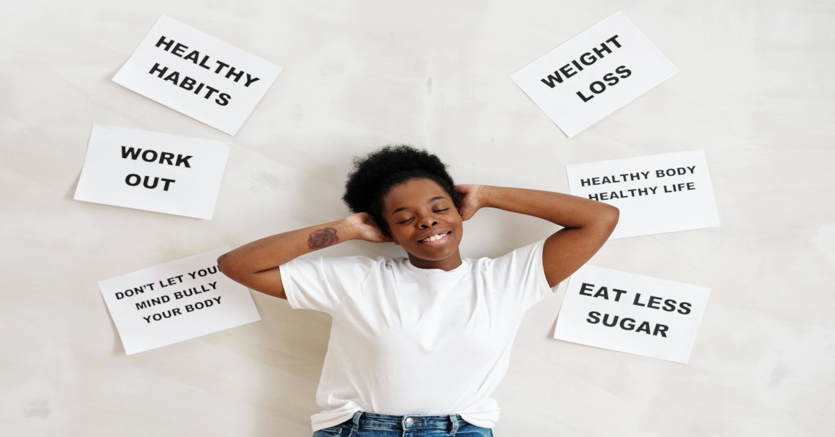 A person smiling while surrounded by cards with healthy habits written on them.