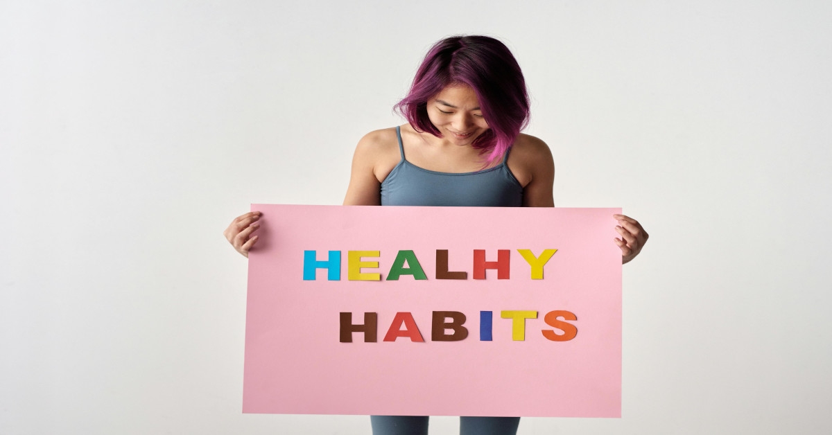 A woman holding a pink poster reading "healthy habits".