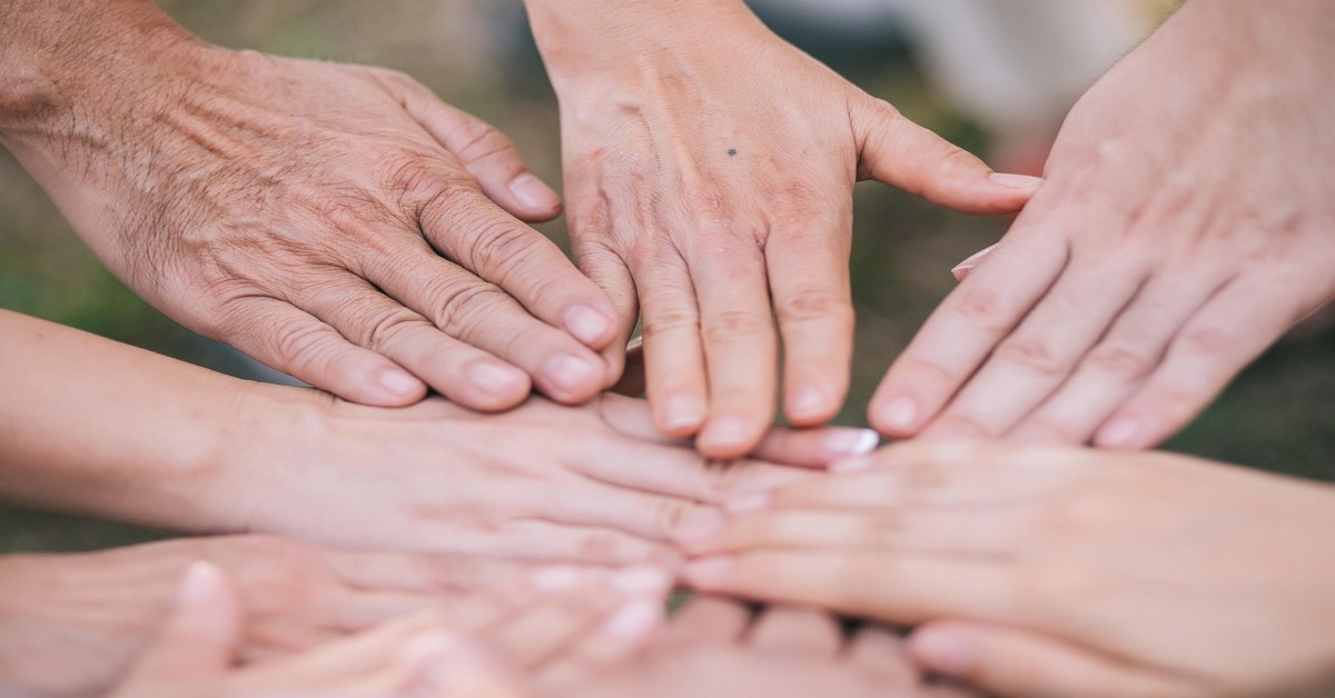 A group of people holding hands together in support.