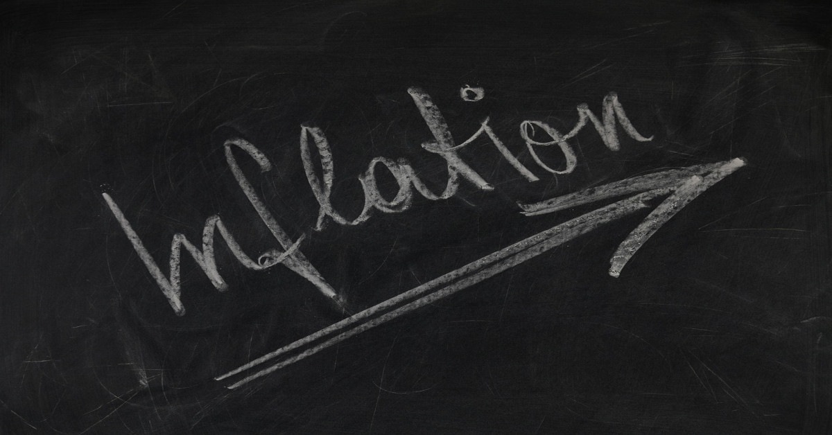 A blackboard with "inflation" written on it with white chalk with an arrow heading up, indicating that inflation is rising.