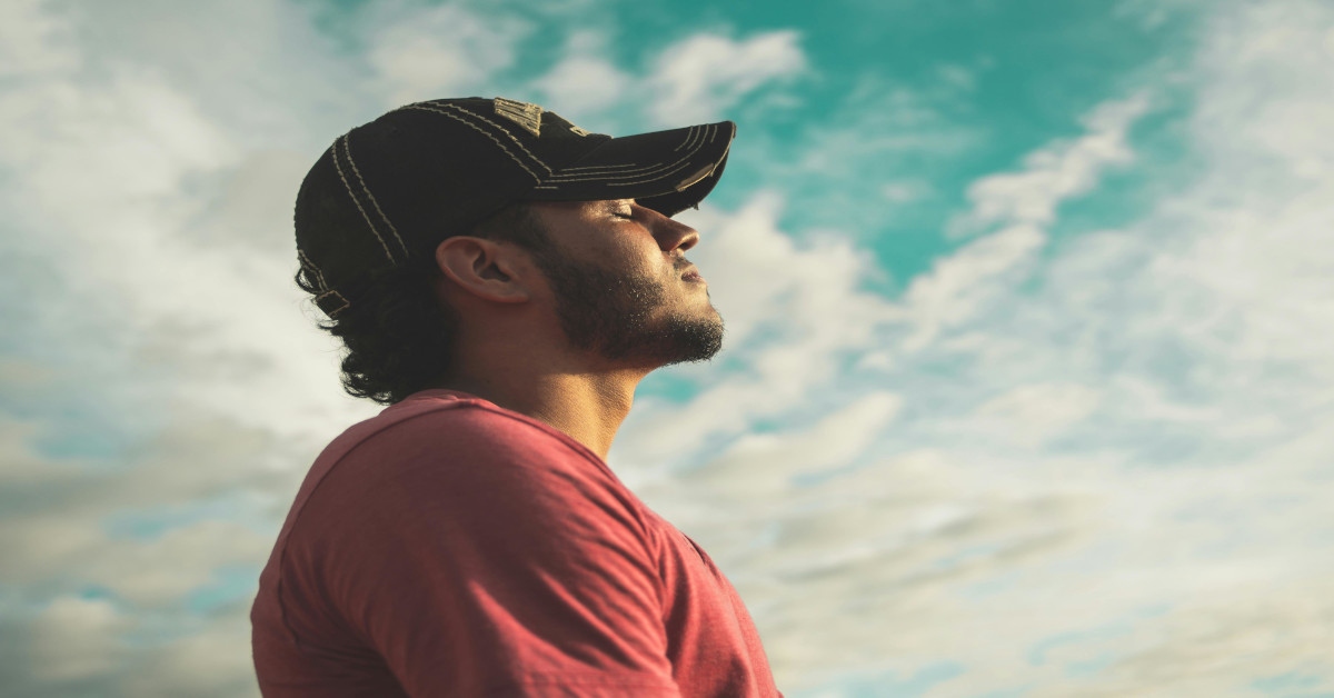 A man standing outside with his eyes closed.