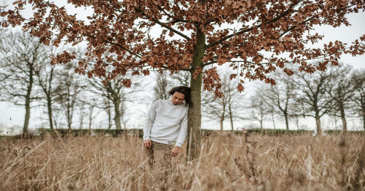 A man looking sad under a tree.