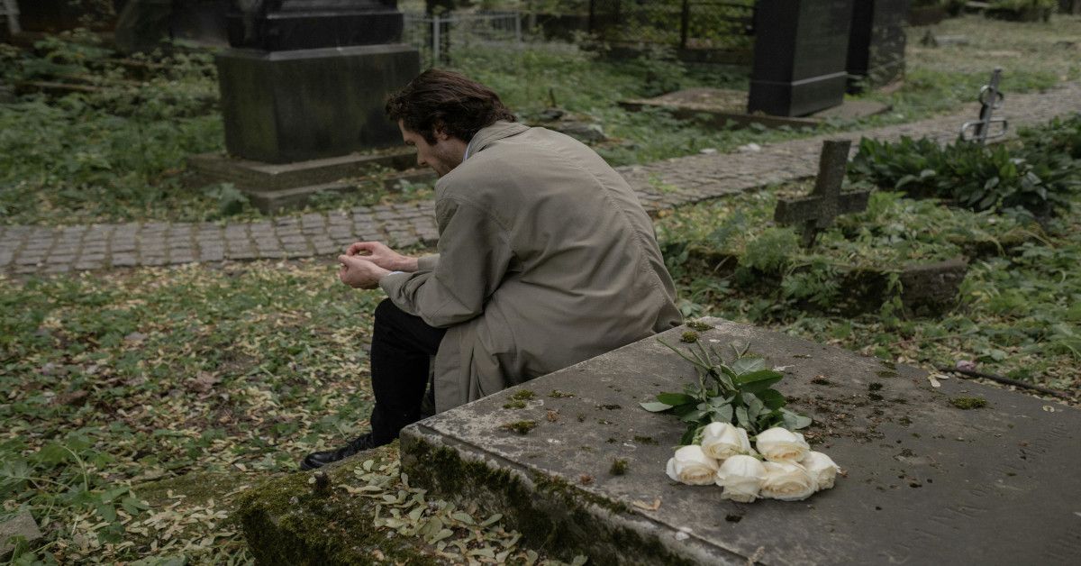 A man sitting by a grave.