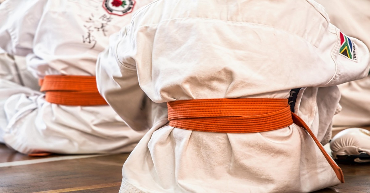 Multiple martial artists sitting on the floor while wearing a Gi.