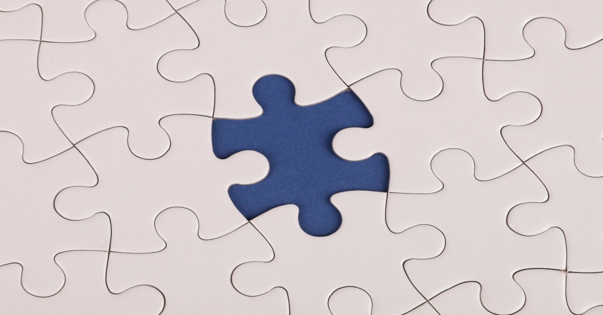 A white puzzle with a missing jigsaw puzzle piece in the middle.