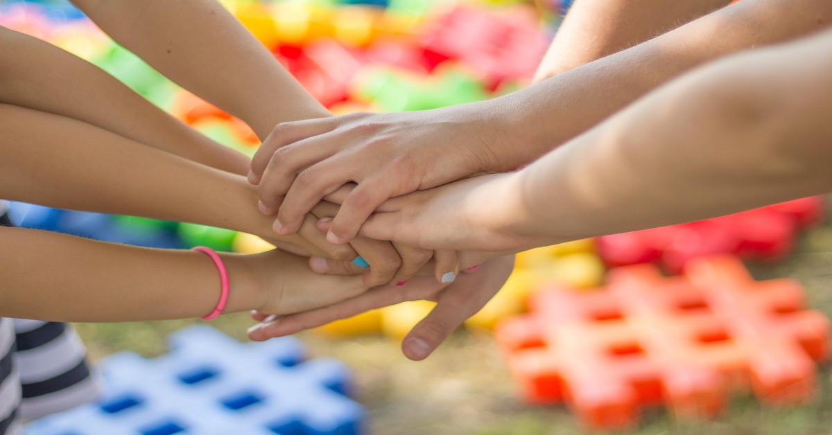 Multiple people holding hands in support.