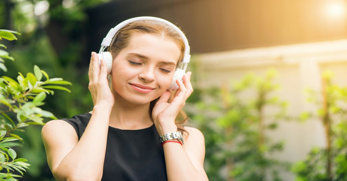 Woman wearing headphones while listening to music outside.