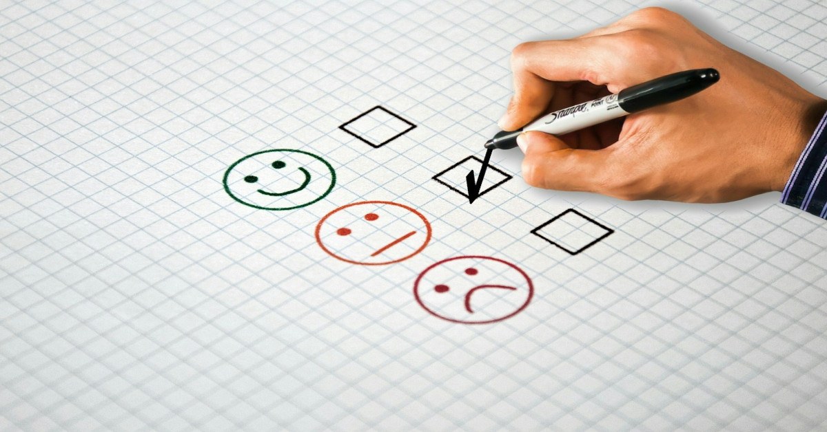 A person selecting a "neutral/blank" face smiley on a survey.