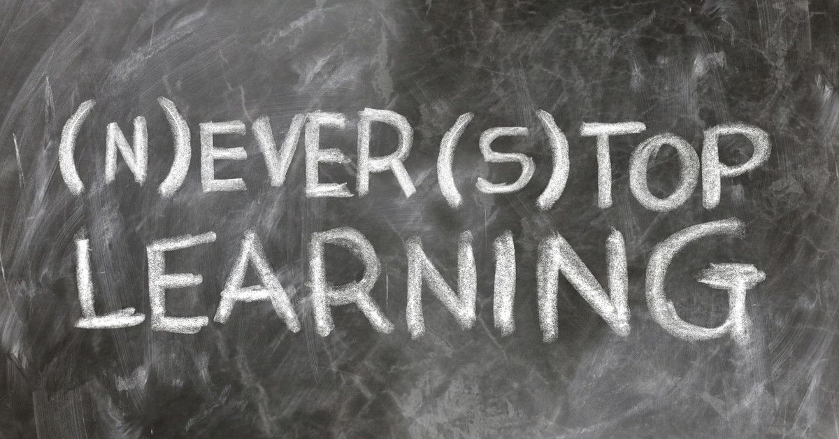 "Never stop learning," written with white chalk on a blackboard.