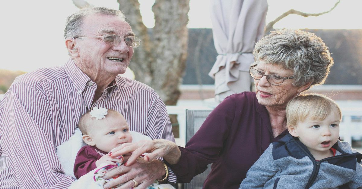 An old couple holding children.