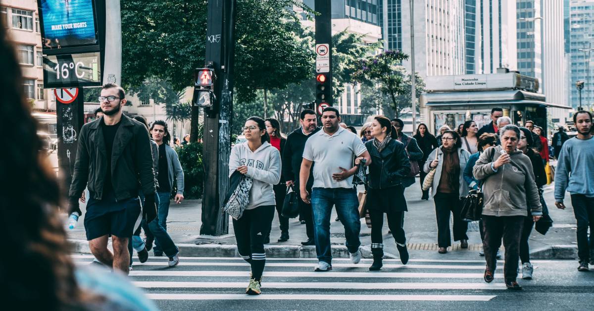 A lot of people walking down the street and crossing a road.