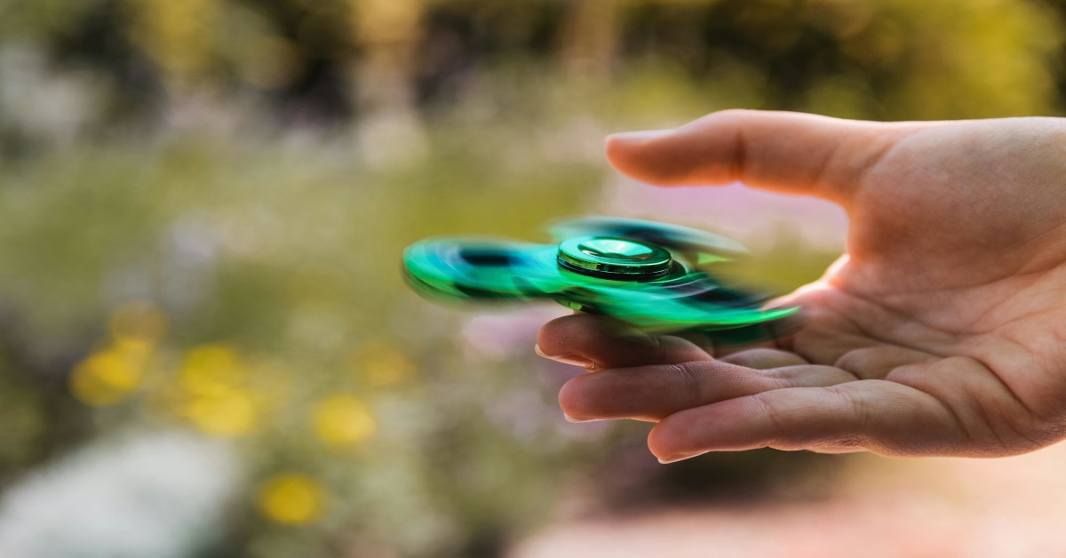 A person playing with a green fidget spinner.