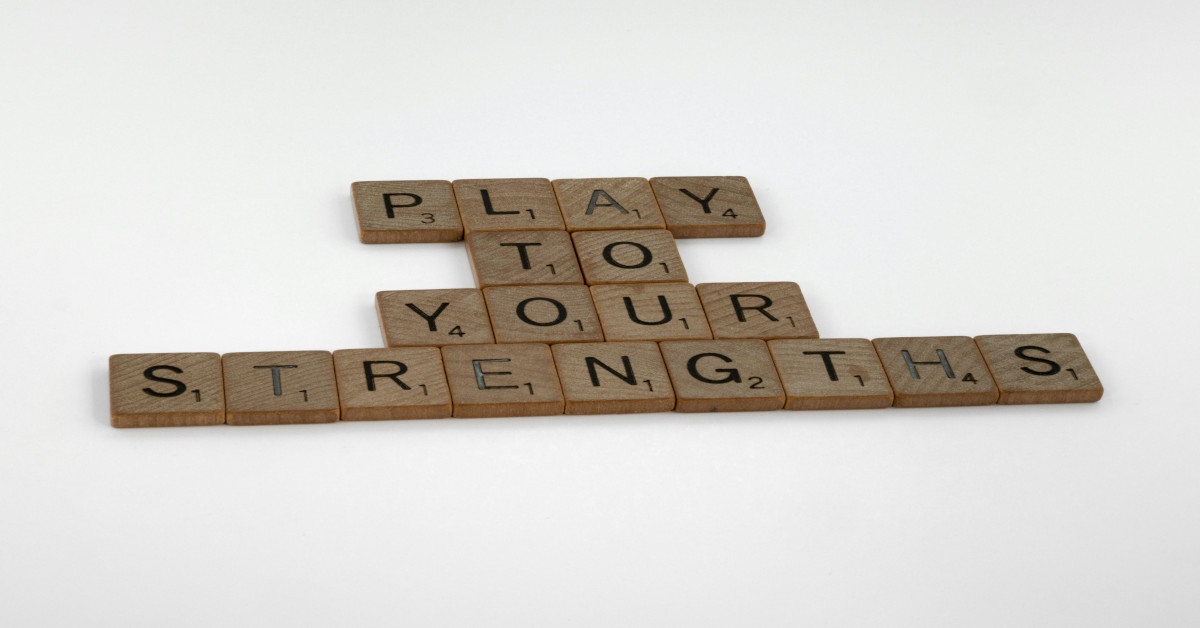 The sentence "play to your strengths" was made with Scrabble blocks on a white background.
