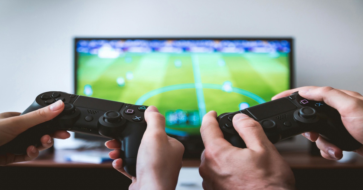 Two people are playing soccer on the television as a video game.