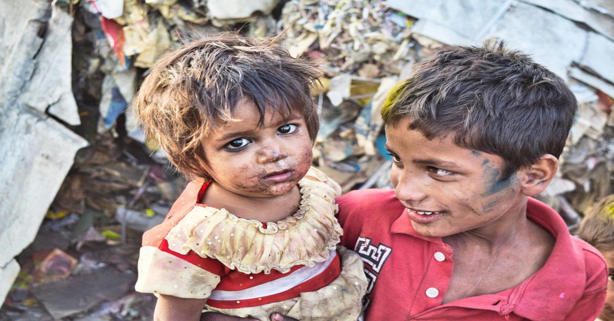 A poor boy holding a poor girl in rough living circumstances.