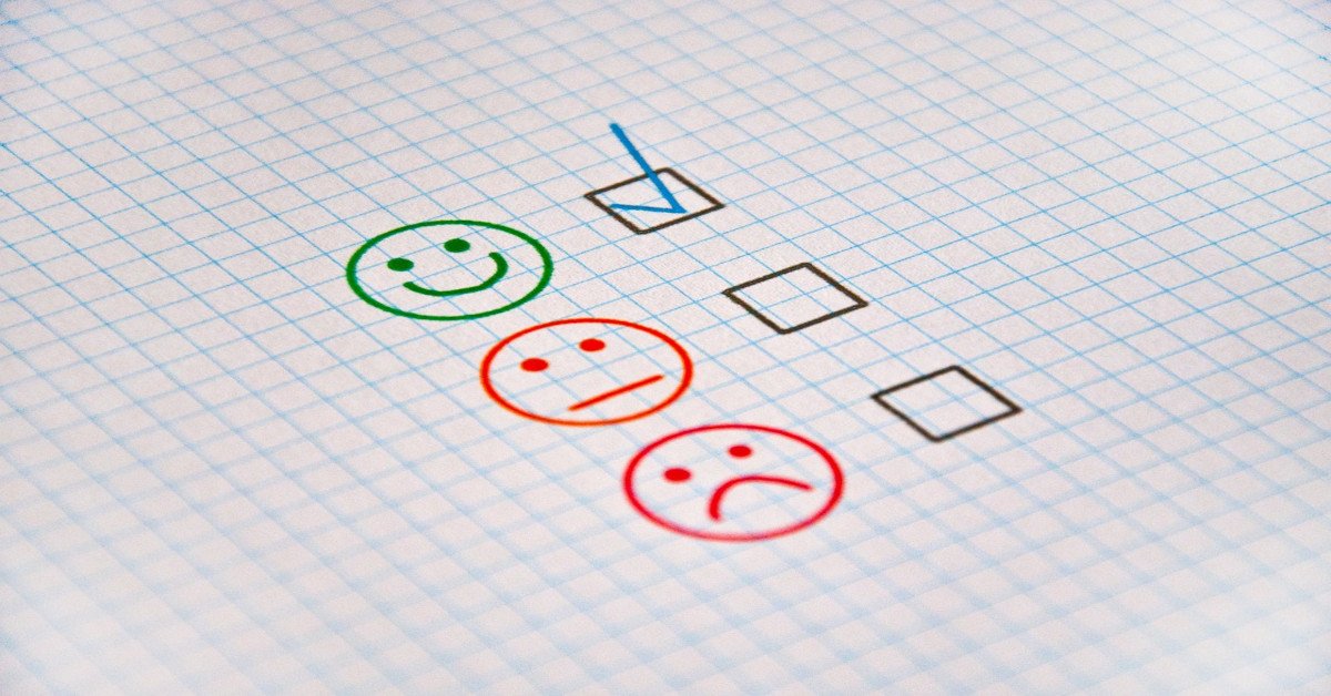 A smiling emoji being crossed on a piece of paper, indicating that the person is happy.
