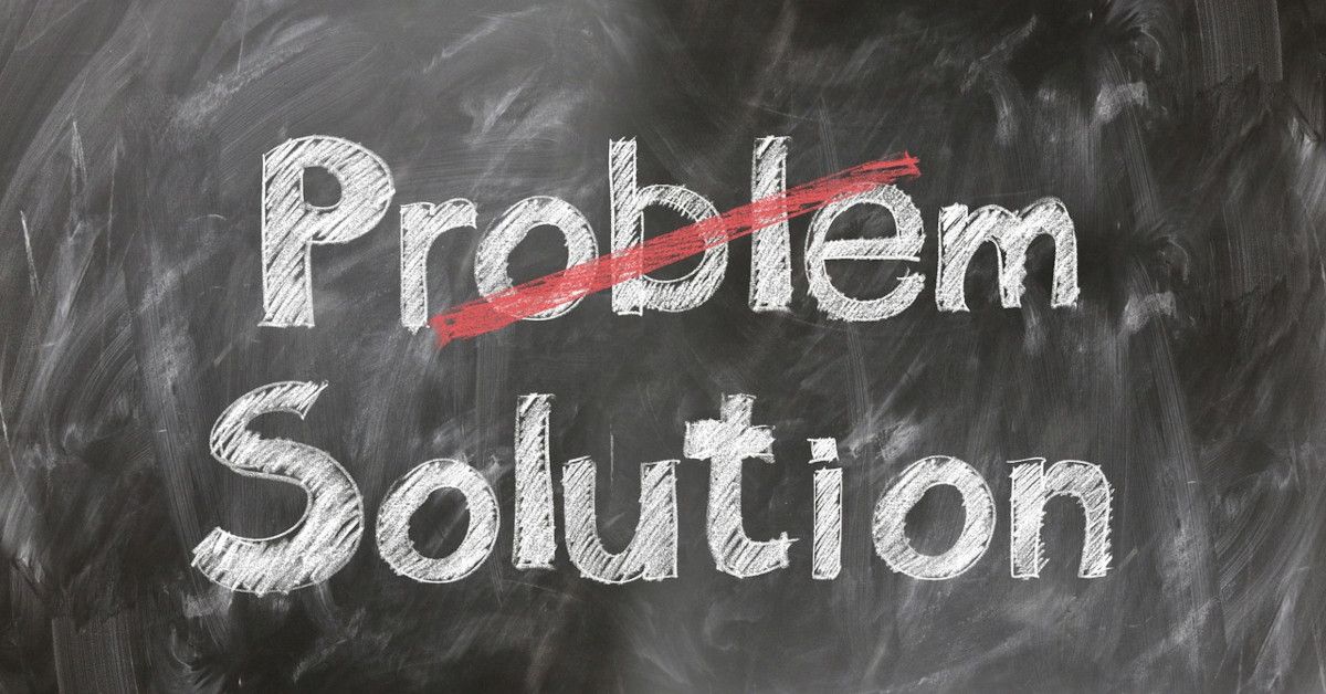 The words "problem" and "solution" are written on a blackboard with white chalk, with the word "problem" crossed out with red chalk.