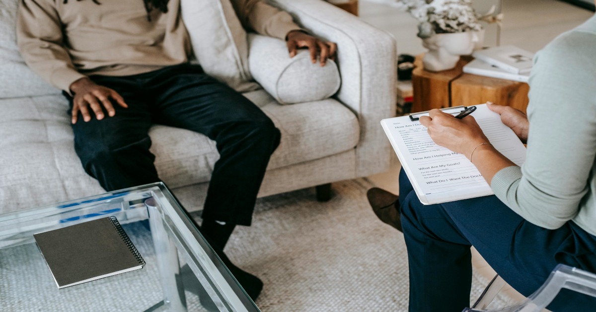A person is talking with a psychologist who is taking notes.