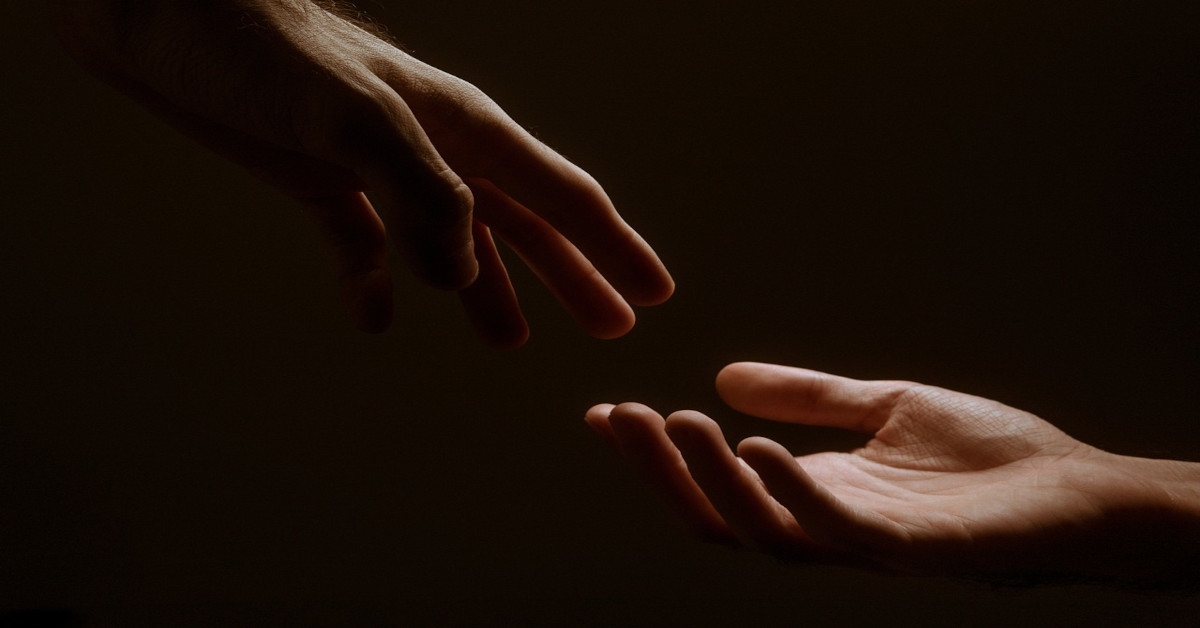 Reaching hands on a black background.
