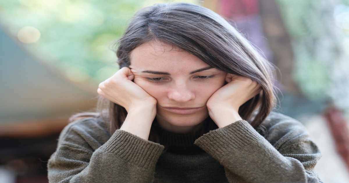 A woman deep in thought while looking sad and holding her head.