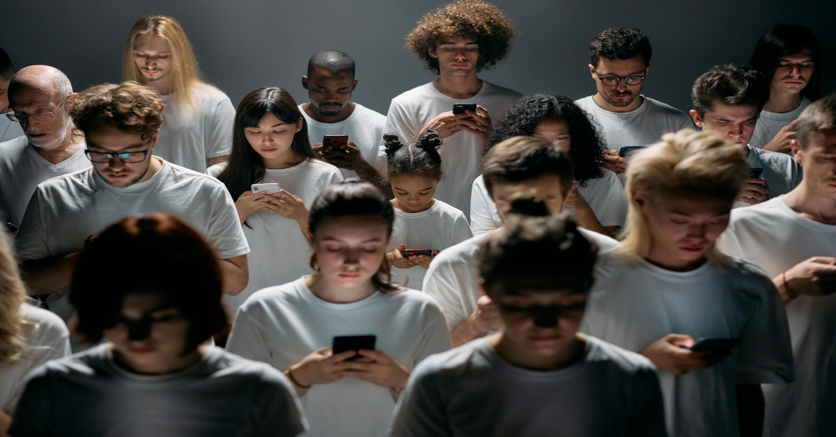 A group of people standing together, only paying attention to their phones while scrolling.
