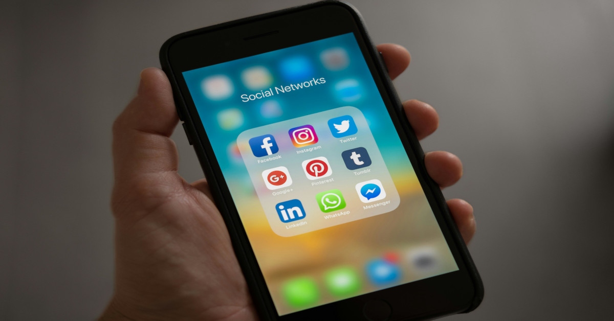 A hand holding a phone saying "social networks" with various social media icons.