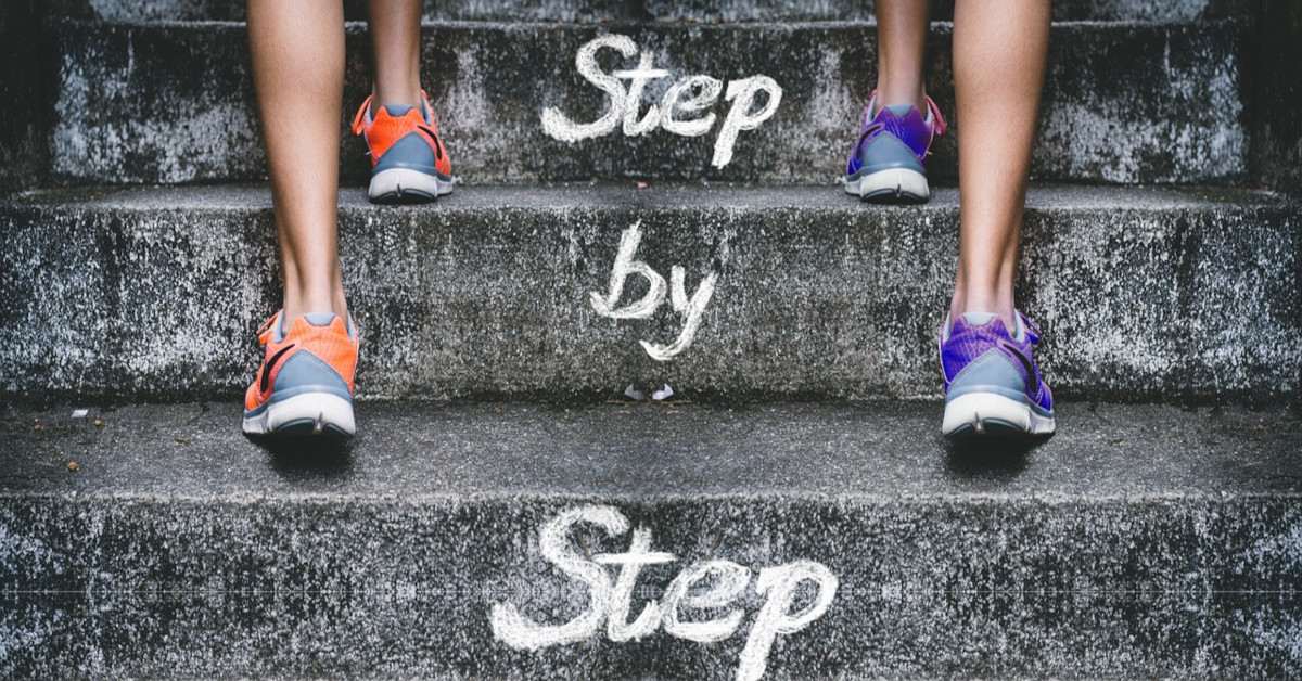 Two people are walking up the stairs with the stairs reading "step by step".