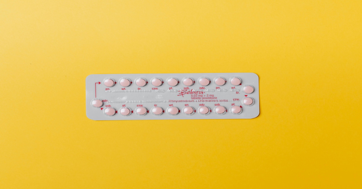 A strip of birth control pills on a yellow background.