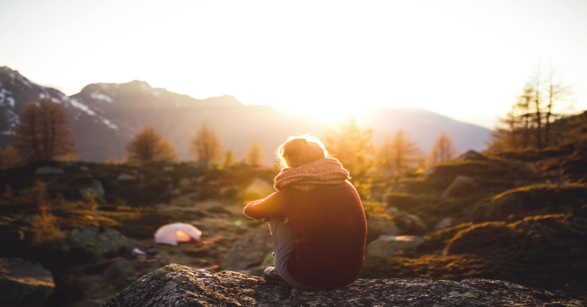 A woman is sitting outside watching the sunlight.